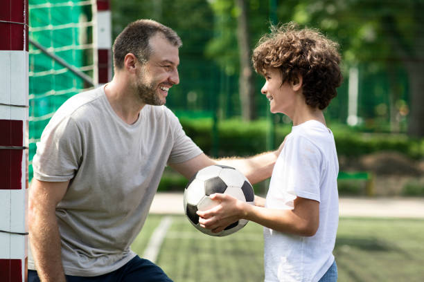 спортивный взрослый папа играет в футбол со своим сыном - child family tutor father стоковые фото и изображения
