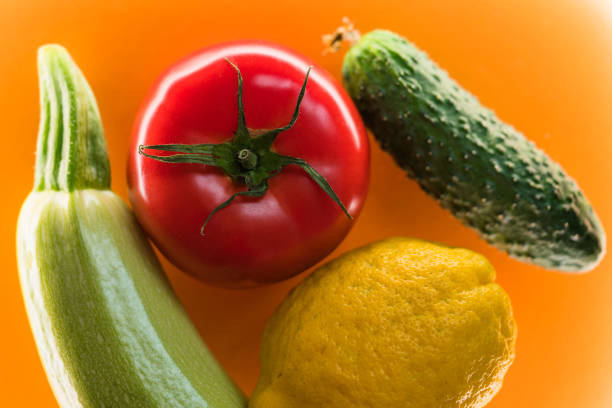 Mix of fresh vegetables and fruit on the colorful background. Cucumber, tomato, zucchini and lemon top view