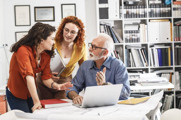istock Senior designer manager explaining to his female coworkers how to solve problem. 1315151302