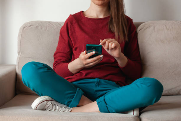 istock Woman using mobile phone, holding in hands sitting on sofa 1315155126