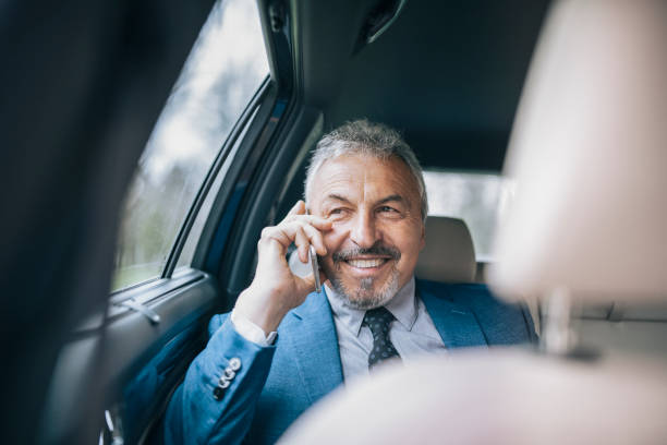 istock Senior businessman using a phone while travel by a car. 1315157494