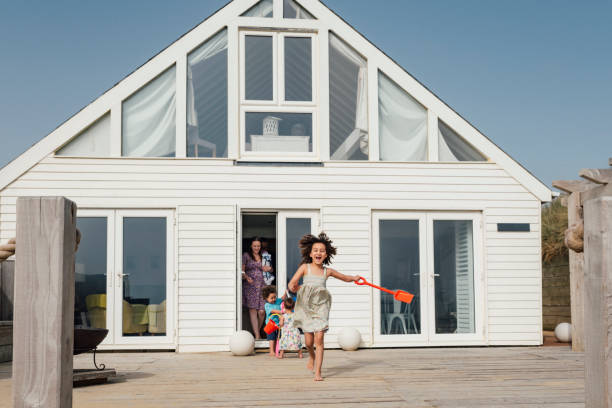 fille d’âge élémentaire de course mélangée menant la famille à la plage - maison de vacances photos et images de collection