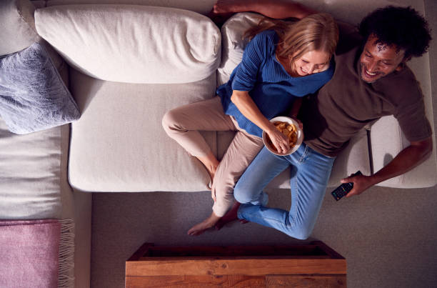 overhead view of mature couple relaxing on sofa at home watching tv together - date night imagens e fotografias de stock