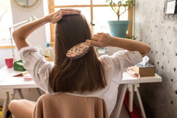 Young woman with combing her beautiful brown hair Rear view of young woman with combing her beautiful brown hair in bedroom combing stock pictures, royalty-free photos & images