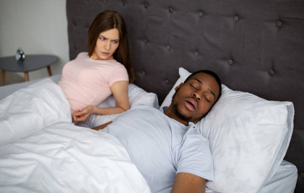 junge schwarze kerl schnnicken und stört seine wütende schlaflose frau im bett zu hause - couple love snoring sleeping stock-fotos und bilder