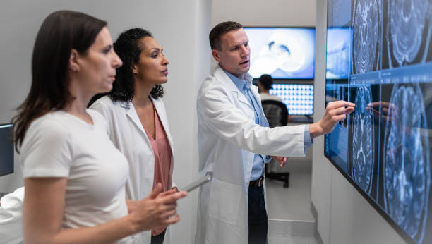 Doctors Consult Over An MRI Scan Small group of doctors consult over an MRI scan. doctor head stock pictures, royalty-free photos & images