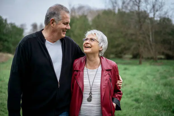 Elderly couple walking in nature and smiling at each other