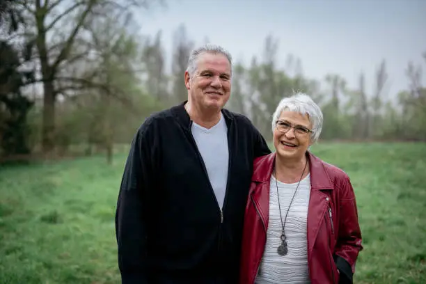 Elderly couple in nature smiling at the camera