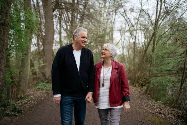 Elderly couple taking a walk in the forest, looking at each other and talking lightheartedly