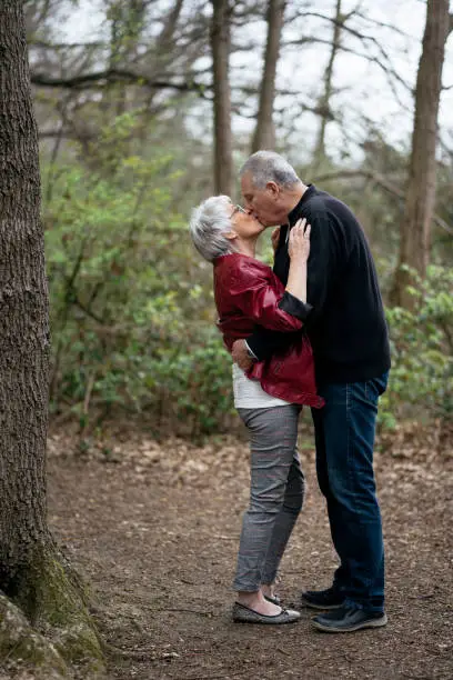 Elderly couple standing in nature, kissing and holding each other