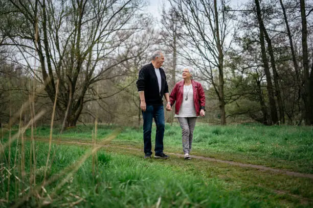 Elderly couple taking a walk in the forest and talking lightheartedly