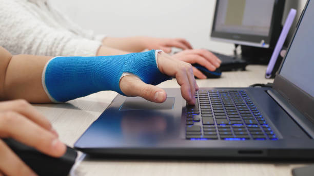 Fiberglass cast hand typing laptop in office