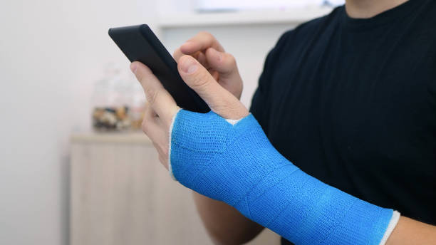 istock Fiberglass cast hand uses phone surfs the internet 1315159793