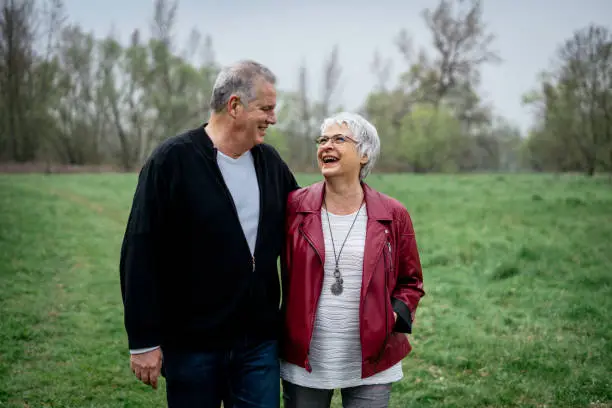 Elderly couple walking in nature and smiling at each other