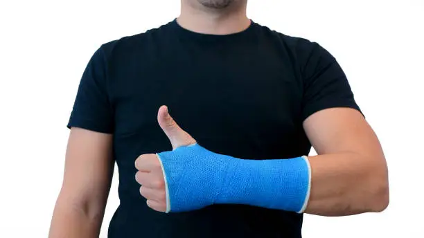 Photo of Man shows thumbs up plaster cast on white background