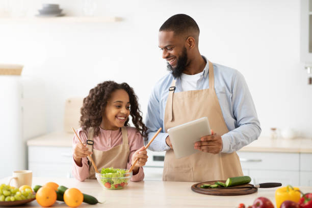 istock Black man and girl cooking in the kitchen using tablet 1315159881