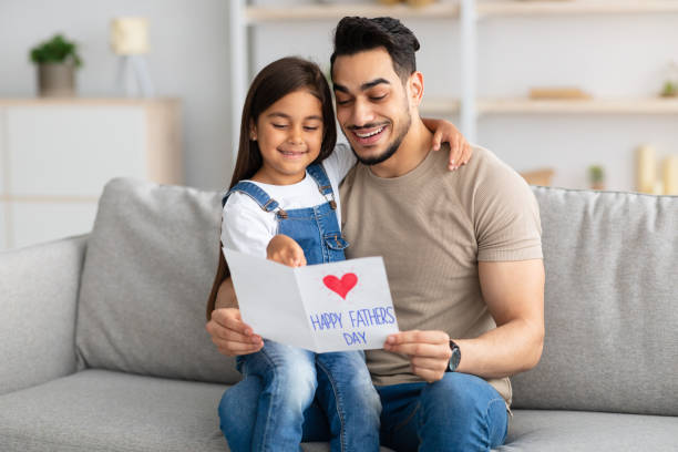 istock Little daughter greeting young excited dad with card 1315164100