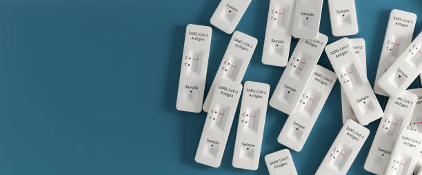 istock Mass testing for Covid-19 / SARS-CoV-2 infection concept: Several rapid antigen test kits. One kit in the middle showing a positive result (two lines visible) 1315165540