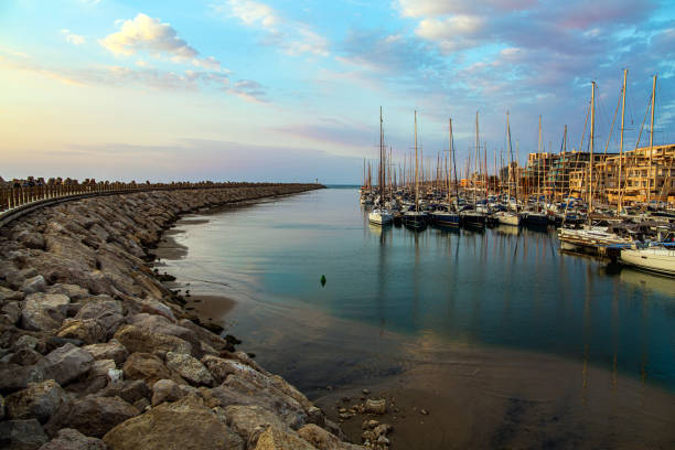 Marina is harbor for yachts, boats and small boats in Herzliya, Israel. Evening twilight on the Mediterranean Sea. Walk along the breakwater that protects the yacht harbor from storms