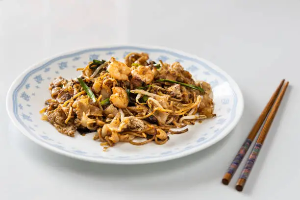Photo of Serving of simple penang char kuey teow is popular fried noodle with coceral, shrimp and eggs in black sauce in Malaysia