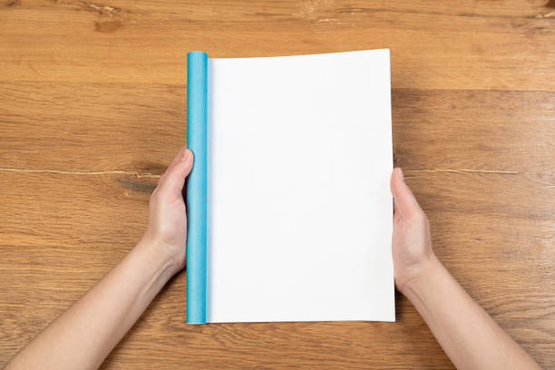 istock Woman's hands open empty catalog, magazines, book mockup on wooden table 1315167844