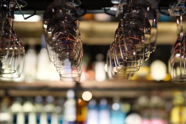 drinking glasses hanging upside down in bar rack at dark night