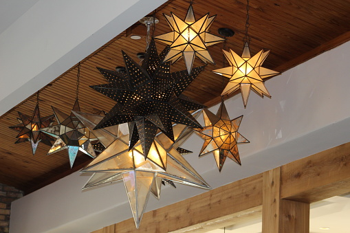 A collection of metallic, multidimensional, star shaped lights hanging from the ceiling.