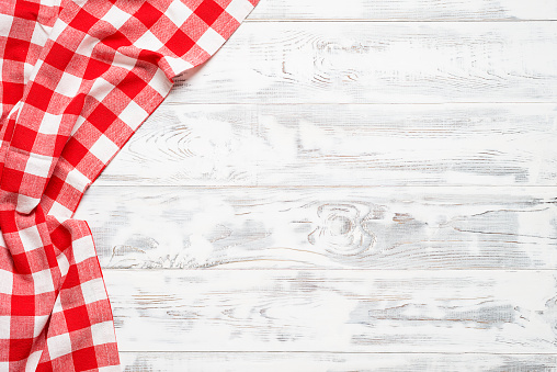 White wooden table covered with red tablecloth. View from top. Empty tablecloth for product montage. Free space for your text