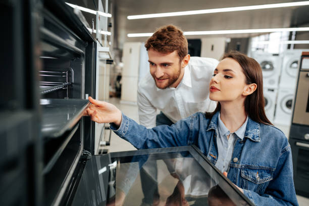 Young couple choosing new electric oven in hypermarket Young couple choosing new electric oven in hypermarket, close up appliance stock pictures, royalty-free photos & images