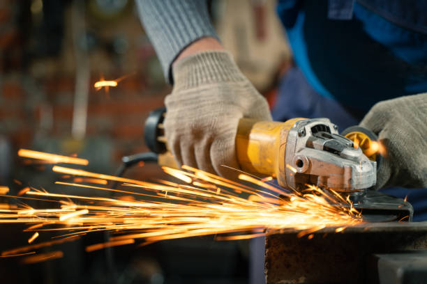 istock Locksmith in special clothes and goggles works in production. Metal processing with angle grinder. Sparks in metalworking 1315180484