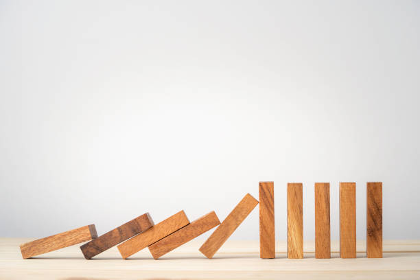 many wooden block dominoes falling to one wooden block standing , resistance and stop risk management concept. - dominó imagens e fotografias de stock