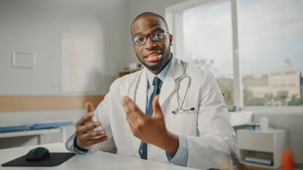 Photo of Doctor's Online POV Medical Consultation: African American Physician is Making a Video Call with a Patient. Black Health Care Professional Giving Advice, Explaining Test Results. Point of View Shot