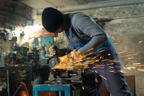 istock Locksmith in special clothes and goggles works in production. Metal processing with angle grinder. Sparks in metalworking 1315187131