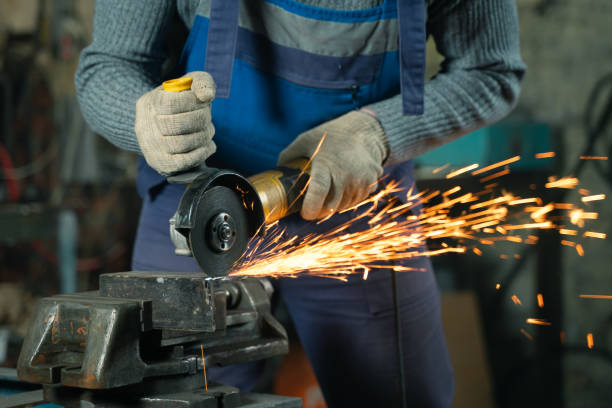 istock Locksmith in special clothes and goggles works in production. Metal processing with angle grinder. Sparks in metalworking 1315187192