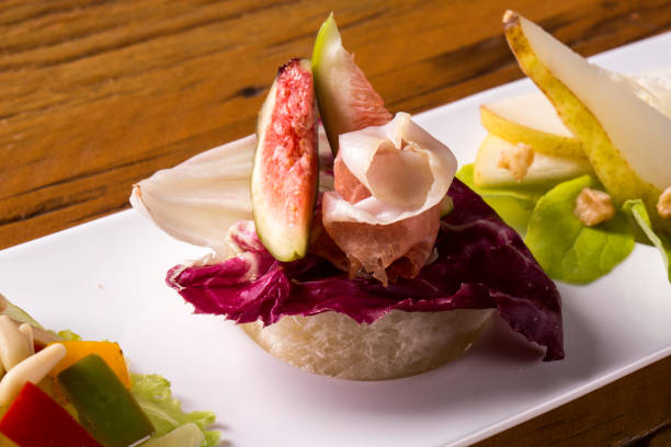 istock Entry dish with parma ham, fig, pear, purple lettuce and fresh grains 1315188871