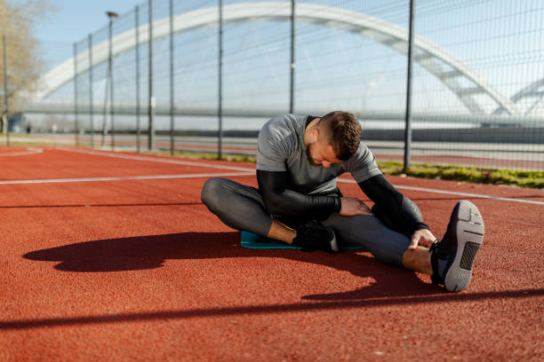 istock Bearded fit man is stretching legs after running near river. Bridge background. 1315189868