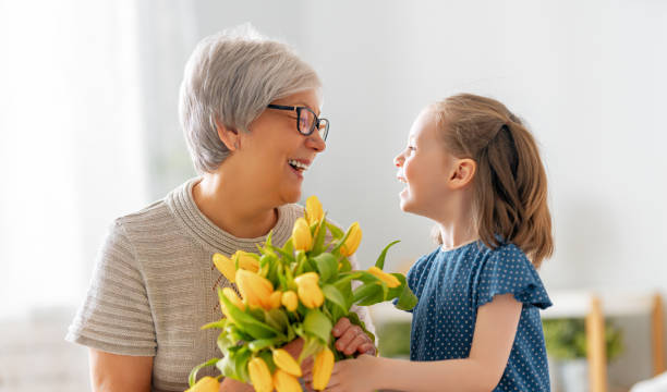 nonna e ragazza sorridenti e abbracciate - grandmother giving gift child foto e immagini stock