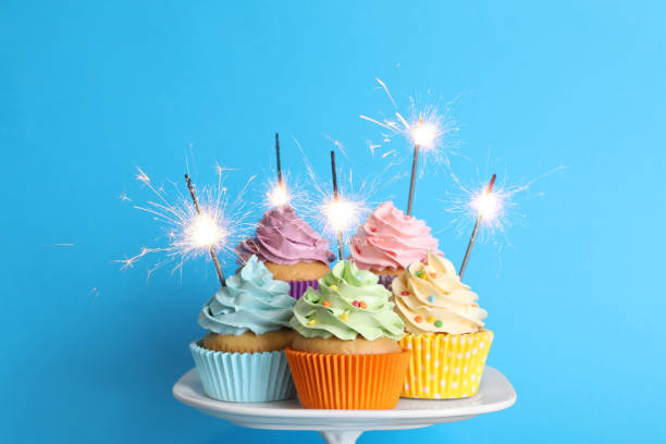 birthday cupcakes with burning sparklers on stand against light blue background - cupcake cake birthday candy imagens e fotografias de stock