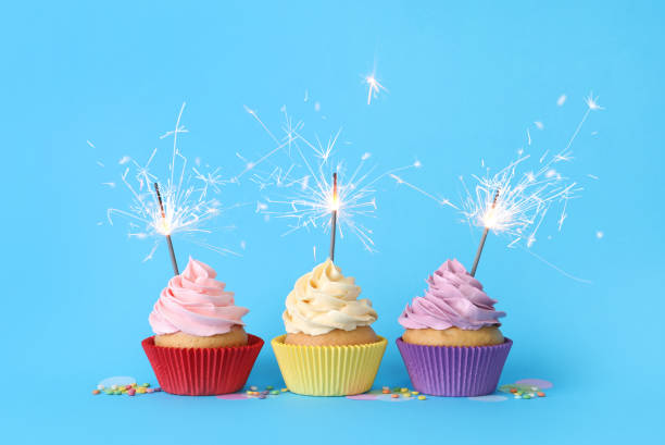 istock Birthday cupcakes with burning sparklers and sprinkles on light blue background 1315195216