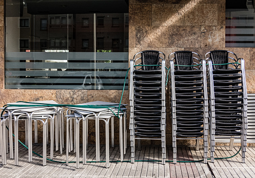 Group of chairs and tables stacked outside a cafeteria. Coronavirus pandemic. Photograph taken on a mobile device.