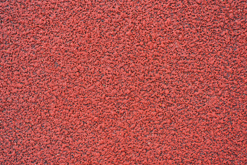 Textured red background, rubber coating for stadiums, running tracks, tennis courts. Top view, close-up