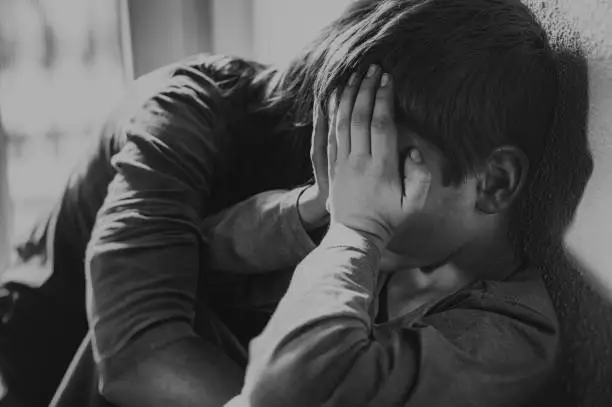 Photo of Child and mother kneel on the floor in sadness or worry and comfort each other