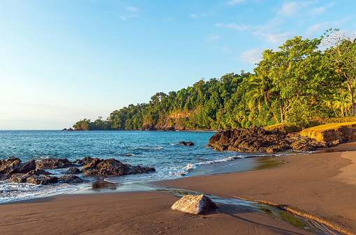 Tropical rainforest beach at sunset by Pacific Ocean, Corcovado national park, Costa Rica.