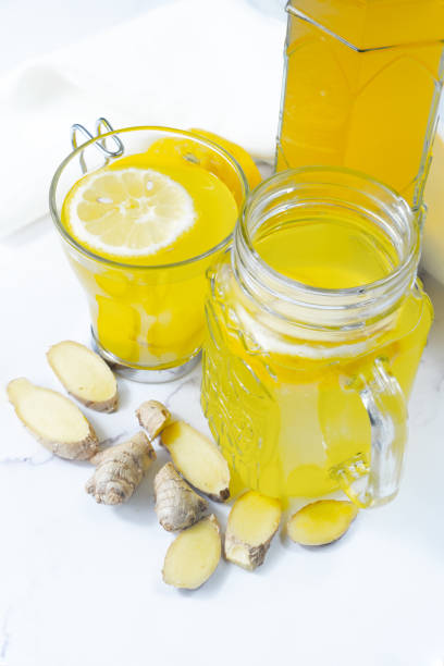 Vertical photo, overhead shot, with two glasses and a bottle with lemon and ginger kombucha: probiotic fermented tea.