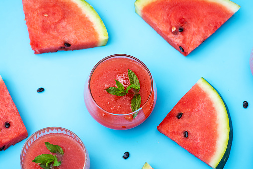 Watermelon slices and fresh juice isolated on blue background flat lay top view
