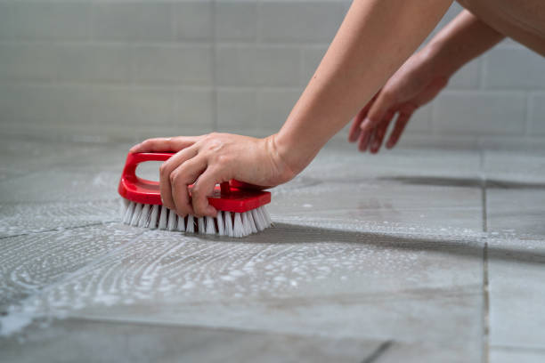 die hand des menschen verwendet bodenbürste, um toilettenmarmorfliesenboden zu reinigen. - red tile stock-fotos und bilder