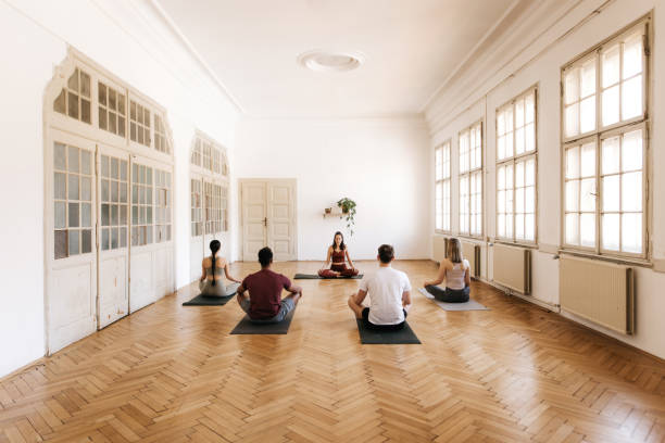 groupe de personnes faisant le yoga dans un studio lumineux de yoga - yoga class caucasian young adult group of people photos et images de collection