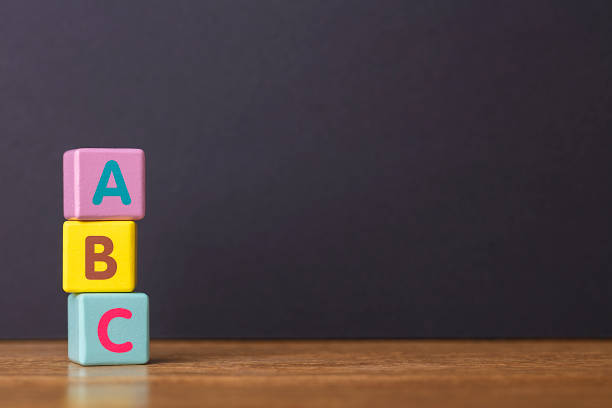 impara il concetto. alfabeto delle lettere abc su tre blocchi di giocattoli in forma di pilastro su tavolo di legno. - ordine alfabetico foto e immagini stock