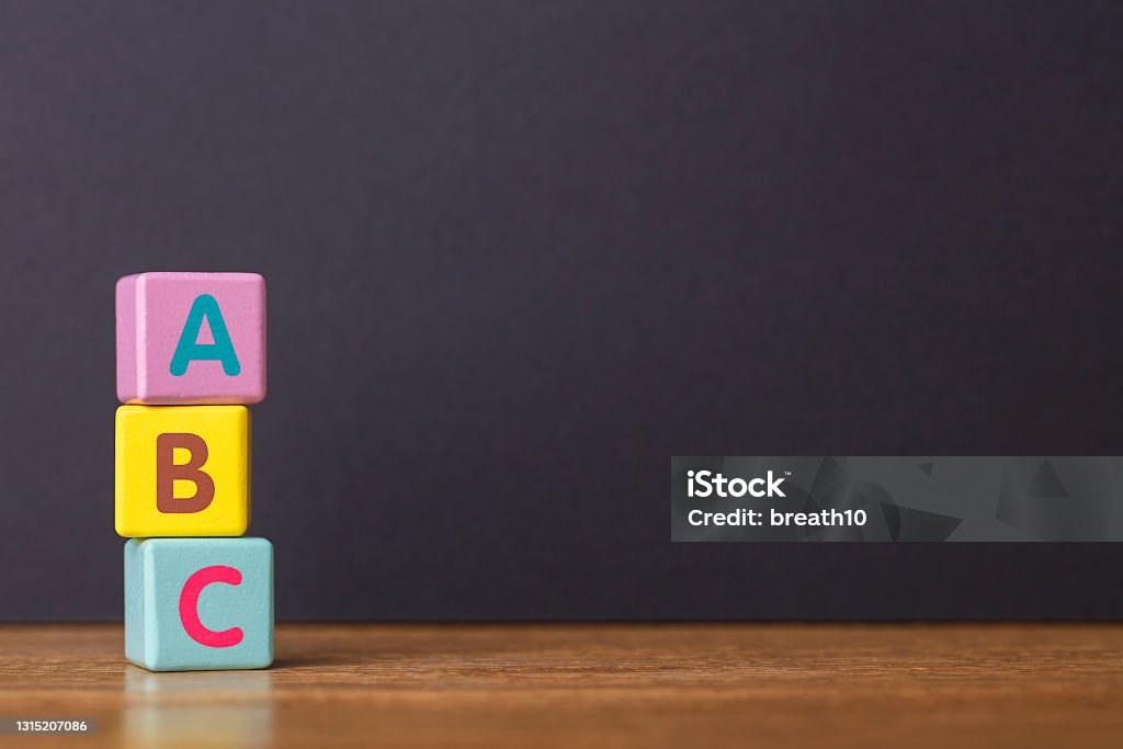 Learn Concept. ABC letters alphabet on three toy blocks in pillar form on wooden table. Learn Concept. ABC letters alphabet on three toy blocks in pillar form on wooden table. Primary school. Basic skills. Reading and writing. Blank space for texts. Toy Block Stock Photo