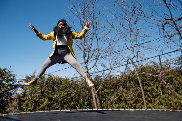 happy woman jumping on trampoline outdoors in springtime. - women jumping bouncing spring imagens e fotografias de stock